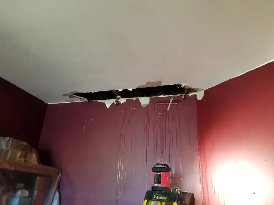 Collapsed ceiling drywall and water streaks down a bedroom wall in Redmond