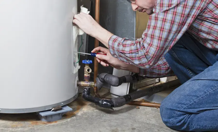 Homeowner checking the valves and wet base of a leaking water heater